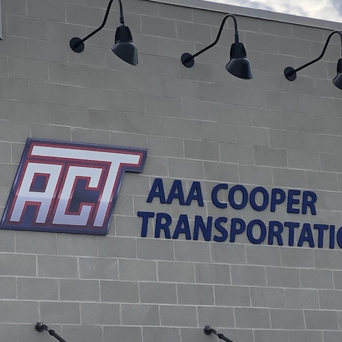 AAA Cooper Transportation signage on the white wall with purple ACT word and light