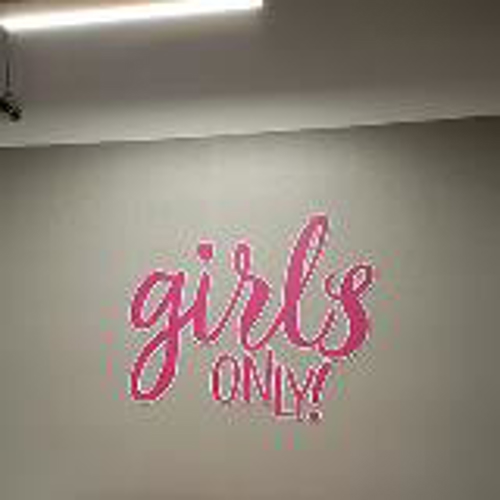 Girls only pink wall mural with sofa and table in a room