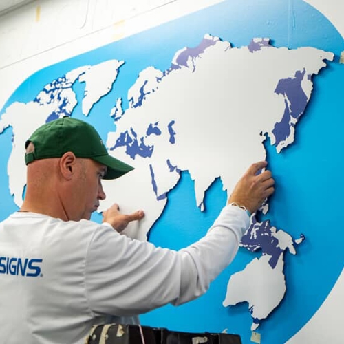 FASTSIGNS employee aligning wall graphic 