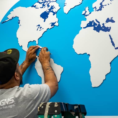 FASTSIGNS employee working on wall graphic
