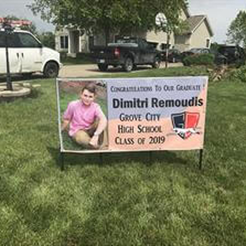 Custom banner for graduate student place on the side of parking space with cars and building at the back