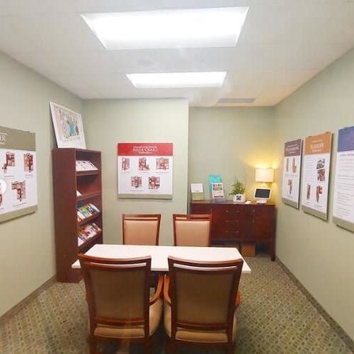 Room with different frames on the wall with tables and chairs