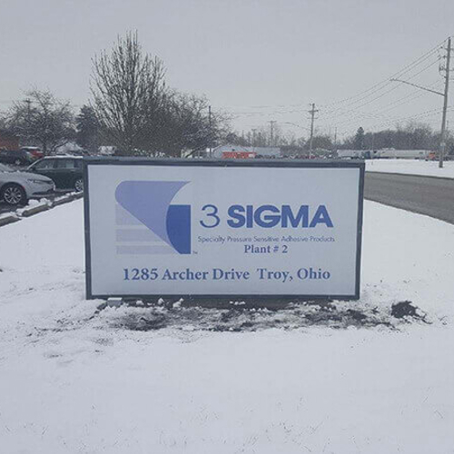 Sigma Exterior Signage on the snow with cars on the parking lot 