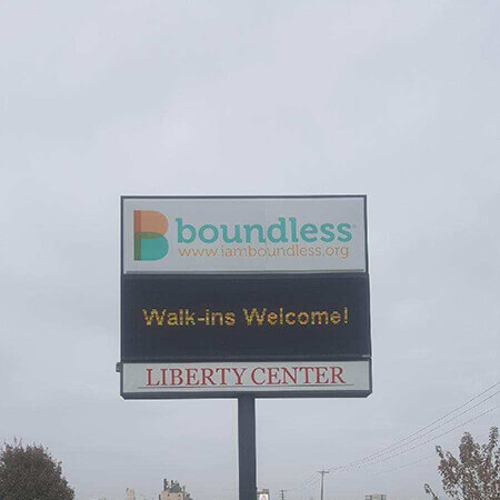 Boundless signage on the middle of the field with trees on the side