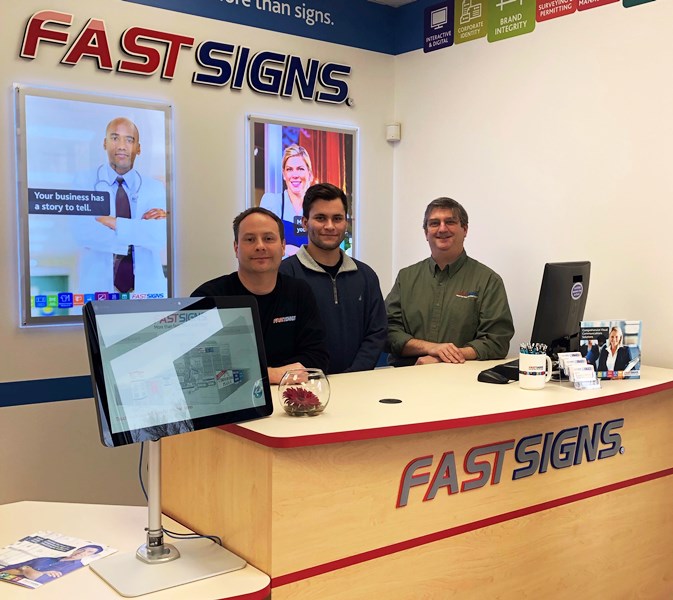 three men at the fastsigns desk