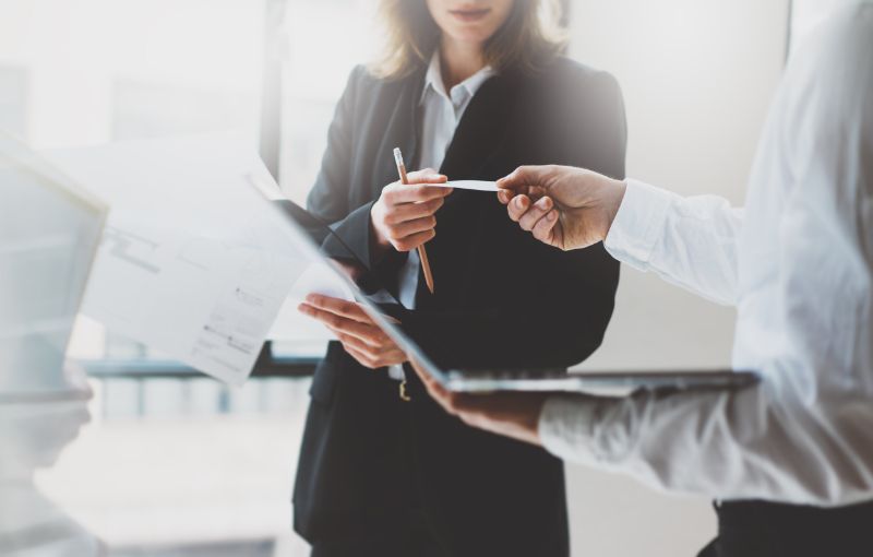 Two professionals hand off a business card