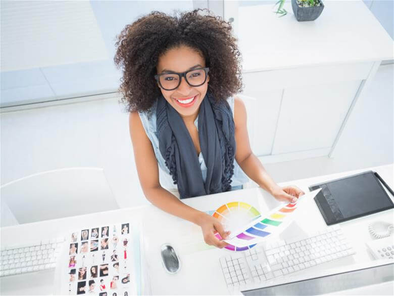 woman with curly hair smiling and holding coloful print out