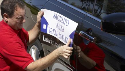 man applying magnetic sign to car
