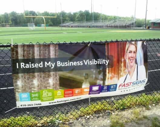a fastsigns banner hangs on a fence