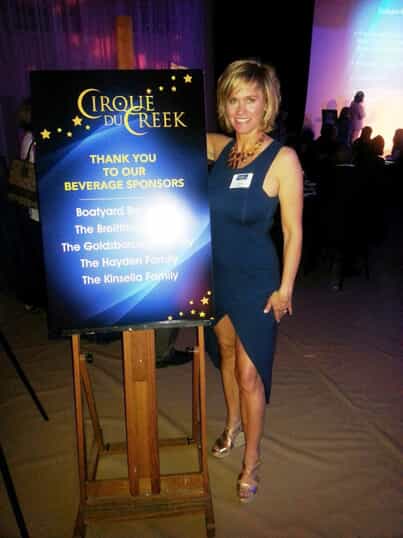 a woman poses with a sign for beverage sponsors